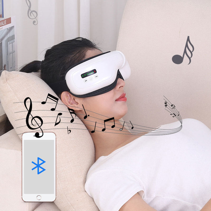 A woman reclines on a beige sofa wearing a white and black eye massager headset. The image includes music note graphics, a smartphone showing a Bluetooth icon, and decorative musical staff lines against a light curtain background.
