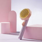 Pink and yellow grooming brush with a white ball on a light pink background