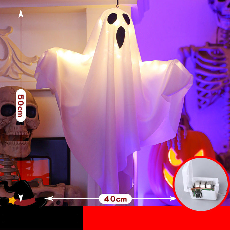 A hanging white ghost Halloween decoration with black eye and mouth cutouts, shown in a decorated room with skeleton props and a pumpkin. White measurement arrows indicate 50 cm height and 40 cm width, with a circular inset showing the battery compartment.